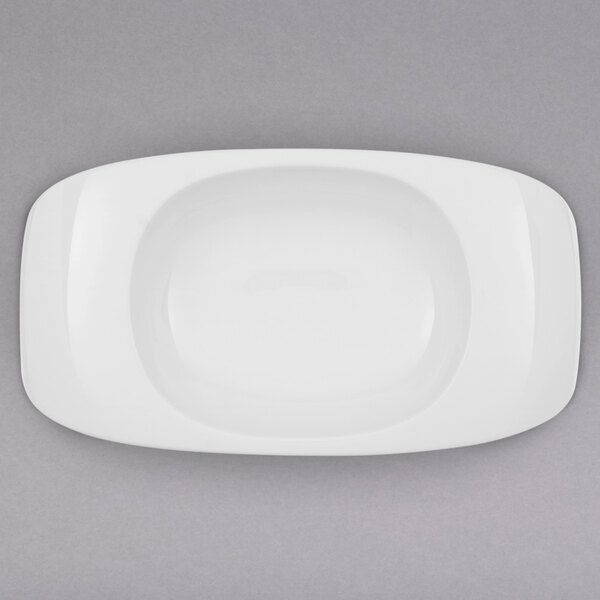 A white rectangular plate with a rounded center and a bowl on top.