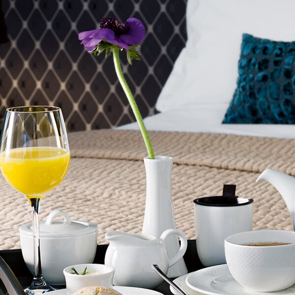 A white Villeroy & Boch porcelain vase on a tray with white dishes and brown liquid.