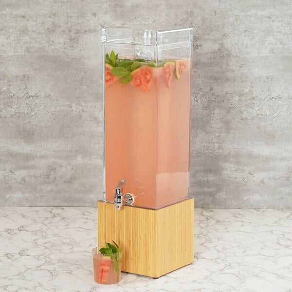 A Cal-Mil bamboo beverage dispenser with a drink in it.