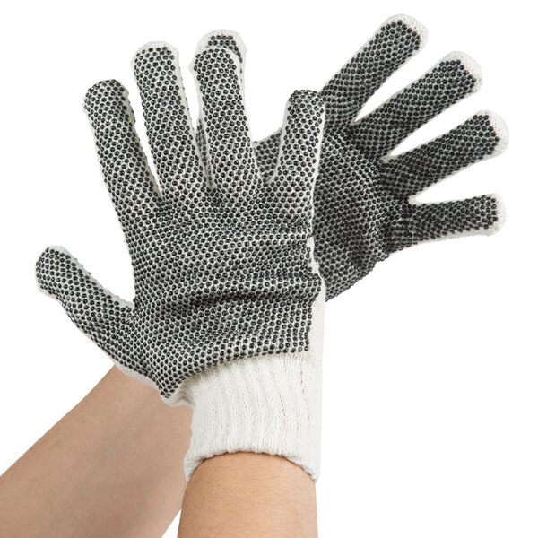 A person wearing Cordova warehouse gloves with black PVC dots on the palm.