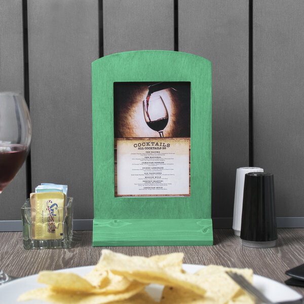 A washed teal wooden frame with a menu in it on a table.