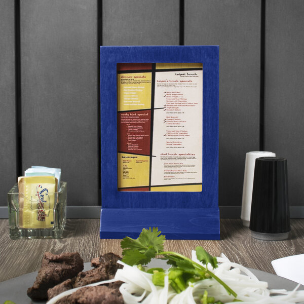 A Menu Solutions True Blue Wood Menu Tent on a table in an Italian restaurant.