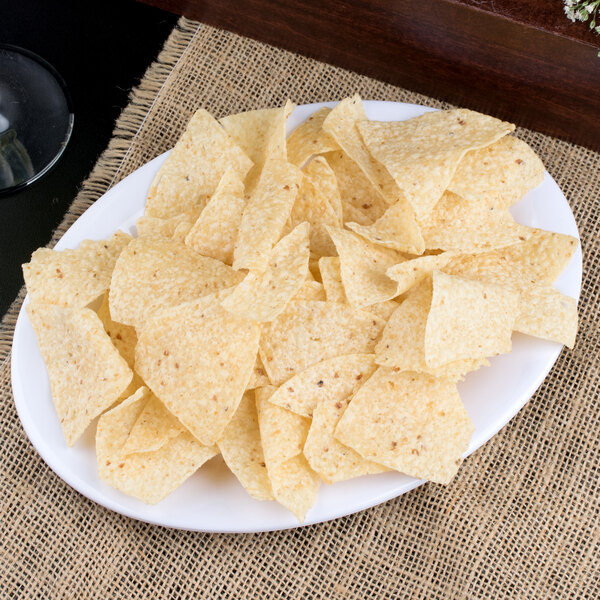 A Carlisle white oval melamine platter with a plate of chips on a table.