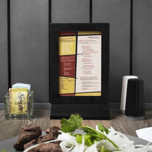 A Menu Solutions black framed wood menu tent on a table.