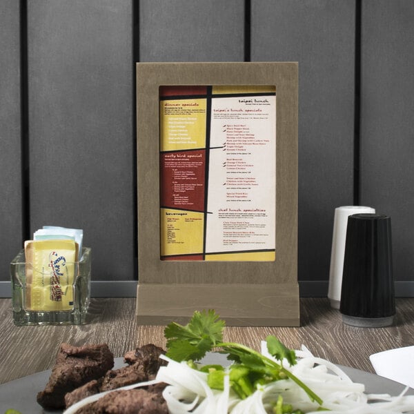 A Menu Solutions weathered walnut wood menu tent on a table.