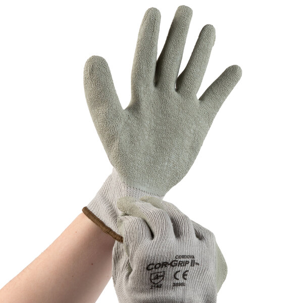 A hand wearing a pair of Cordova gray and white grip gloves.
