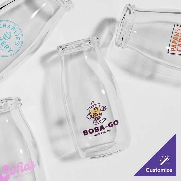 A group of empty Acopa glass milk bottles with logos.