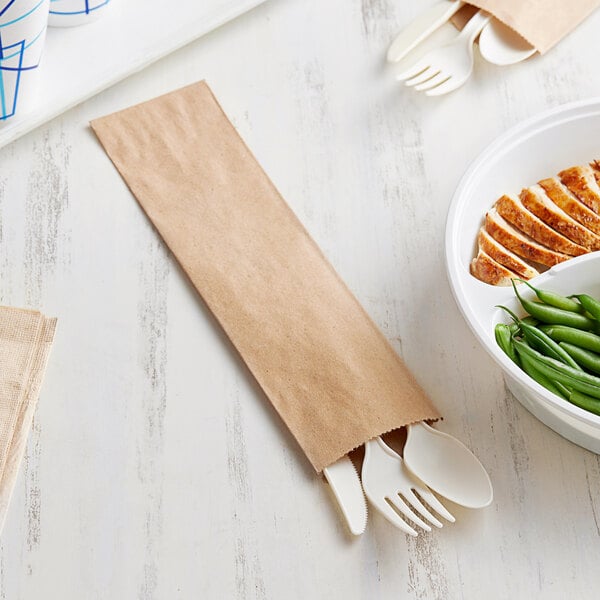 A white plate with a fork and spoon next to a paper bag containing Choice brand silverware.