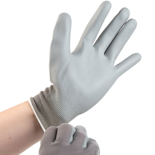 A person wearing Cordova gray warehouse gloves with a grey palm.