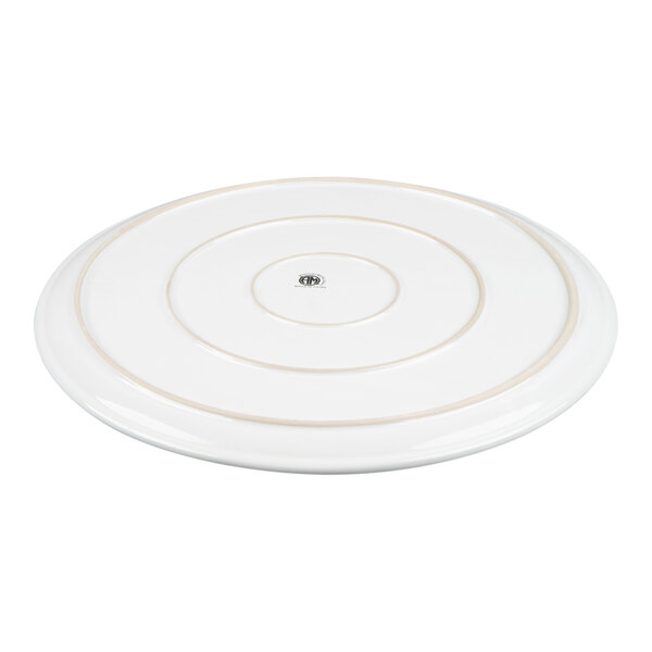 A round, white ceramic tray with concentric circular grooves and a small central logo.