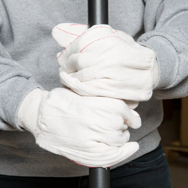 A person wearing white Cordova economy weight work gloves holding a pole.