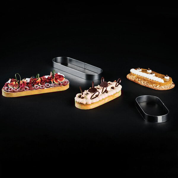 A group of desserts in oval molds on a black surface.
