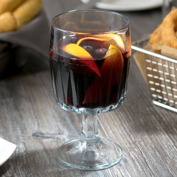 An Anchor Hocking Breckenridge goblet of wine with fruit and a basket of bread on a table.