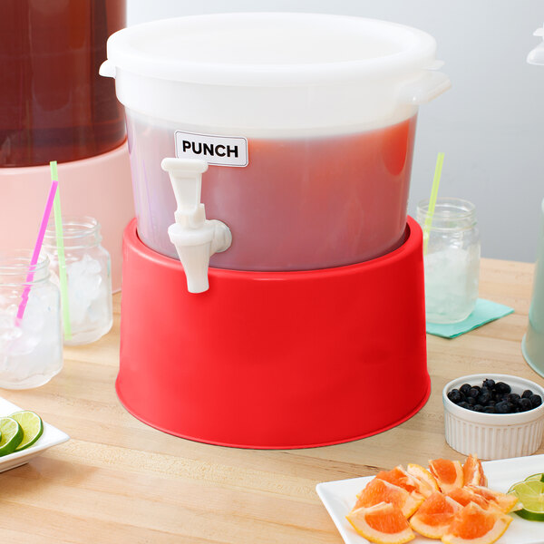 A red round beverage dispenser base supporting a plastic drink container with a spigot.