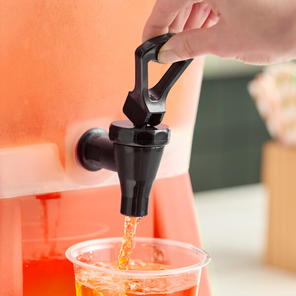 A red 5-gallon beverage dispenser with a black spigot dispensing juice into a clear plastic cup.