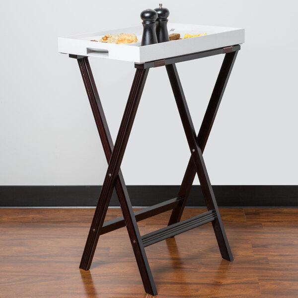 A Carlisle walnut tray stand holding a white tray with salt and pepper.