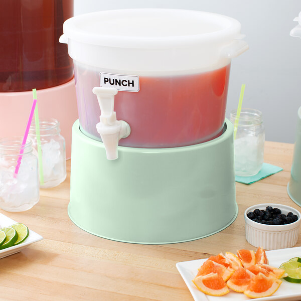 A Choice round beverage dispenser base with a drink dispenser and orange slices on a table.