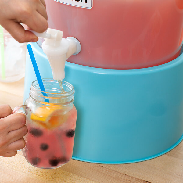 A hand pouring a drink into a Choice Blue beverage dispenser on a counter.