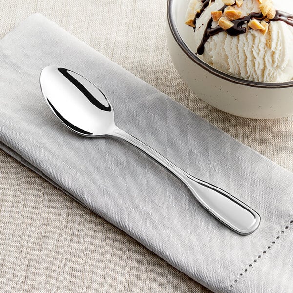 An Acopa Scottdale stainless steel teaspoon on a napkin with a scoop of ice cream.