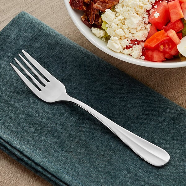 An Acopa stainless steel salad fork next to a bowl of salad.