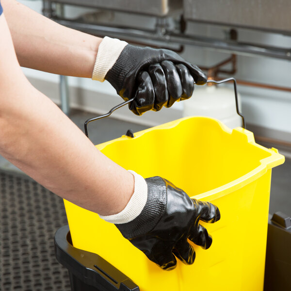 A person in Cordova black PVC gloves holding a yellow bucket.