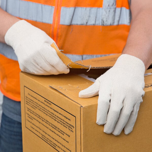 A person wearing Cordova standard weight polyester/cotton canvas work gloves opening a box.