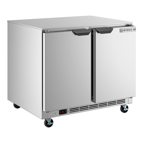 A stainless steel, low profile undercounter refrigerator with two doors and caster wheels.