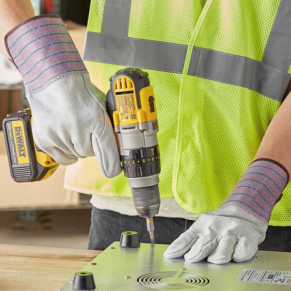 A person using Cordova leather work gloves to drill holes in a metal surface.