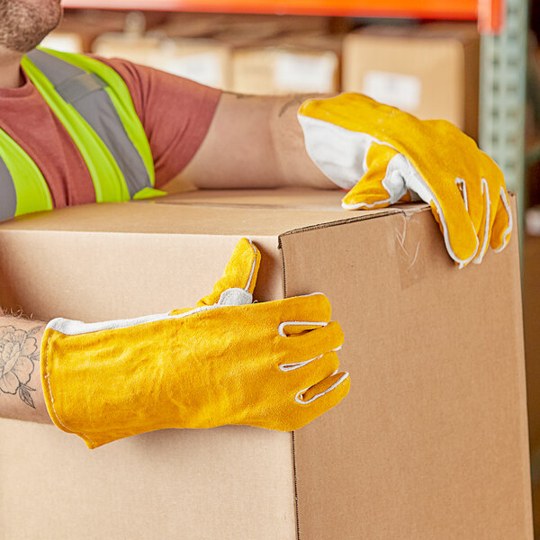 A man wearing Cordova brown and gray leather gloves holding a box.
