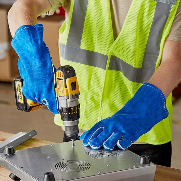 A man using Cordova blue leather welder's gloves to operate a drill.