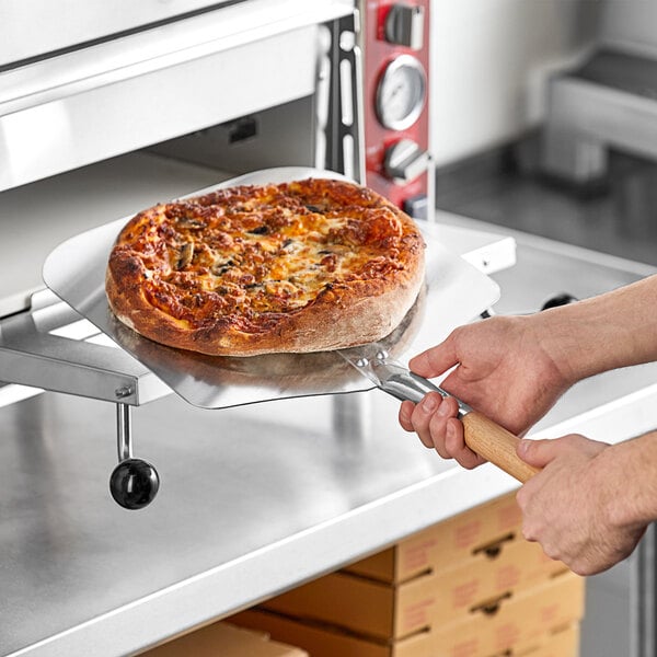 A person holding a pizza on a pizza pan.