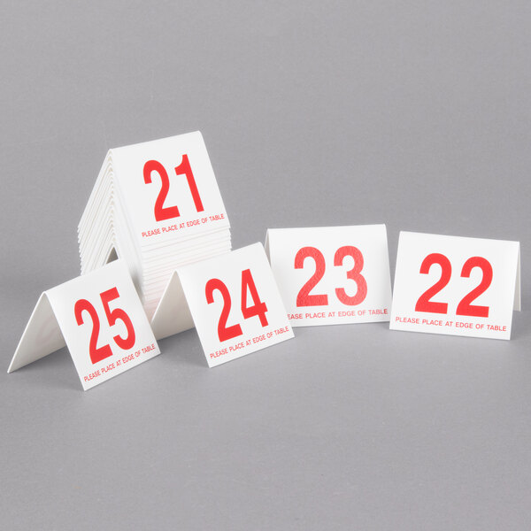 A stack of Cal-Mil white and red double-sided number table tents with red numbers on white cards.