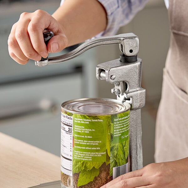 A light duty manual can opener being used to open a large can.