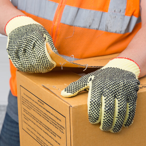 A person wearing Cordova Aramid/Cotton grip gloves holding a box.