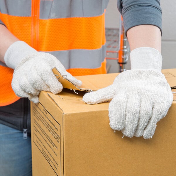 A person wearing Cordova beige work gloves opening a box.