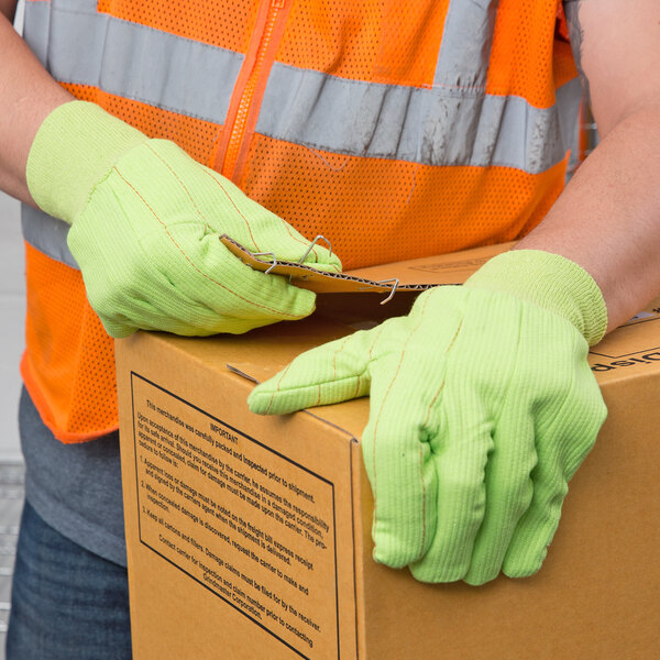 A person wearing Cordova Hi-Vis yellow work gloves holding a box.