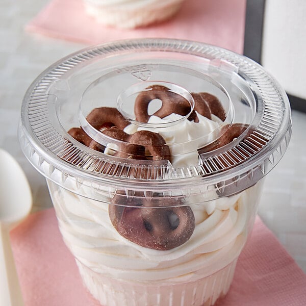 A clear plastic bowl with a chocolate donut and pretzels in it.