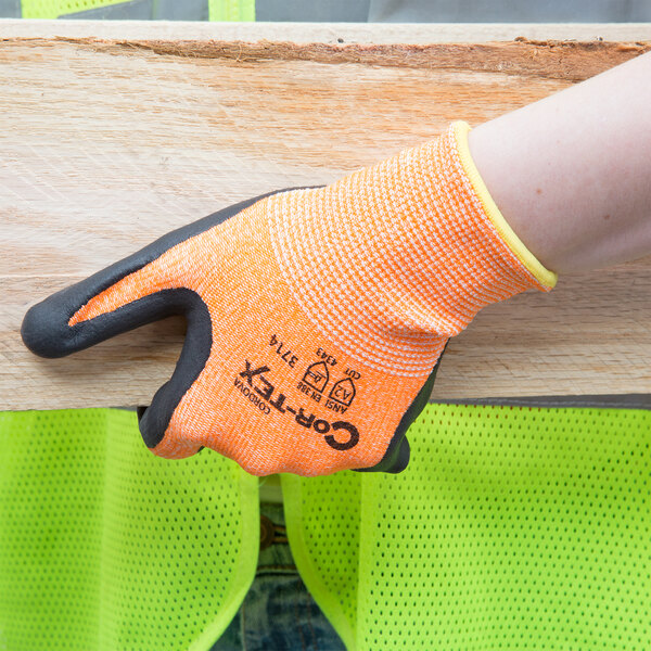 A person holding a pair of Cordova Hi-Vis orange warehouse gloves.