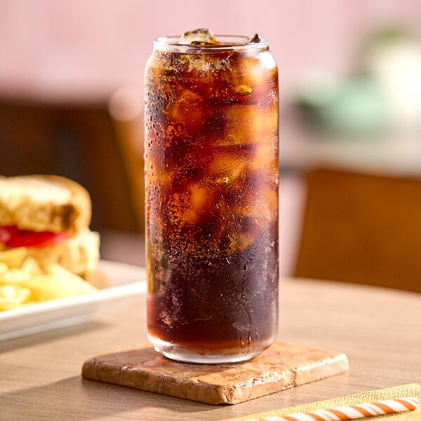 A tall glass of iced cola beverage on a coaster.