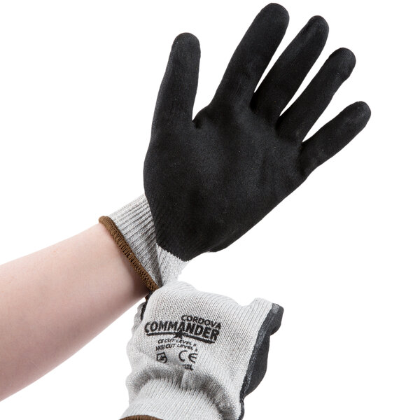 A pair of hands, one wearing a black and white glove and one wearing a black and grey glove.