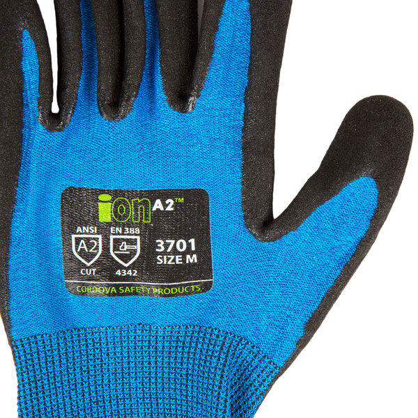 A close up of a Cordova Sapphire Blue work glove with black nitrile coating on the palm and a black and white logo.