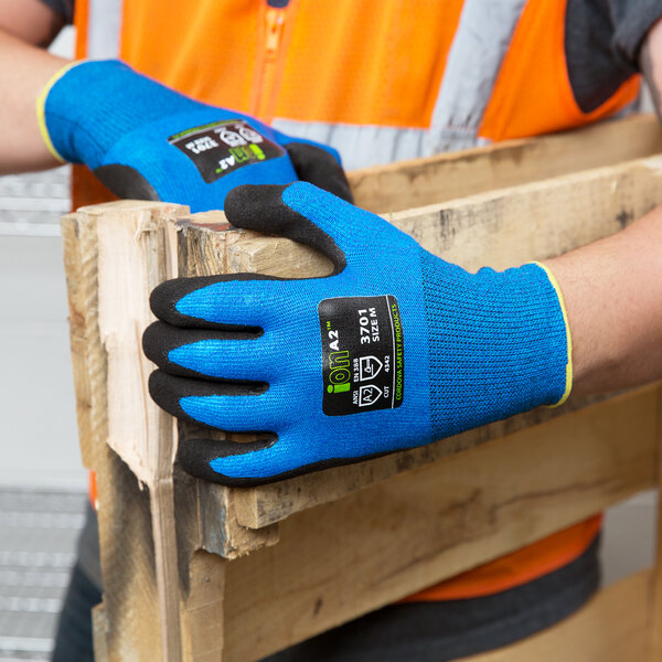 A person wearing Cordova iON sapphire blue gloves holding a piece of wood.