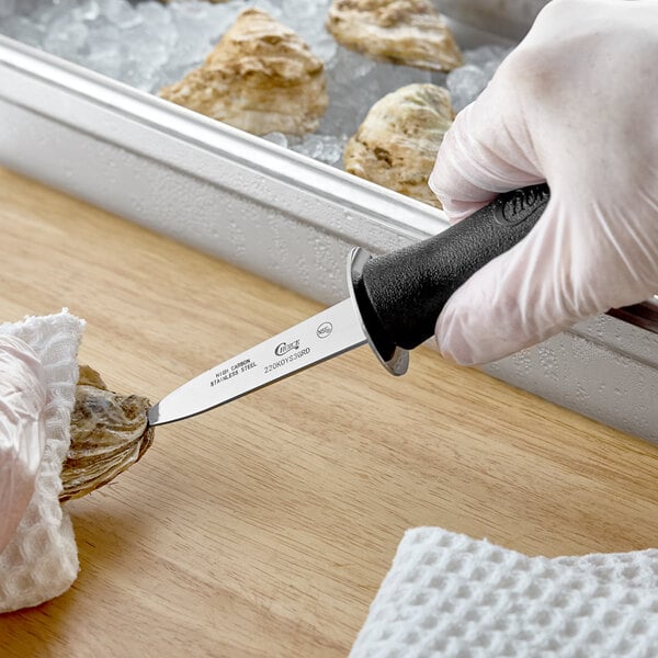 A 3-inch Boston style oyster knife with a guard and a black handle being used to open an oyster.