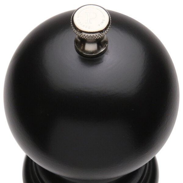 A black round pepper mill with a silver knob.
