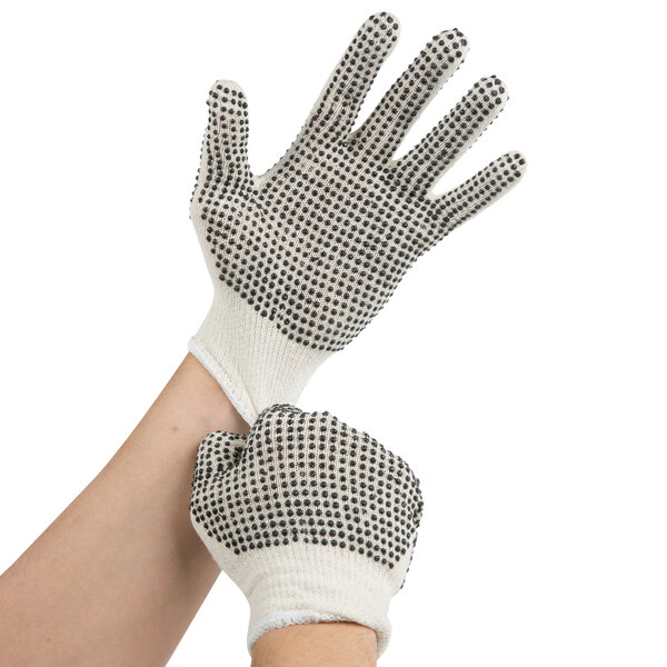 A pair of hands wearing white Cordova work gloves with black dots on the palms.