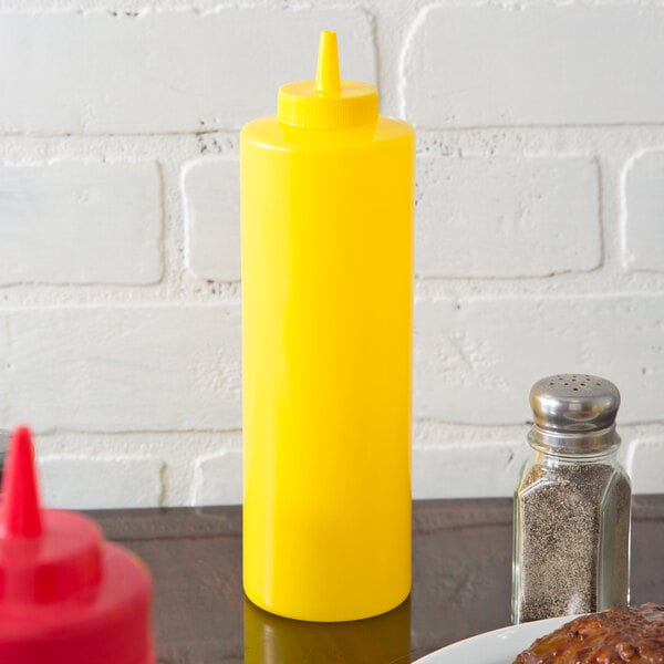 A yellow Choice squeeze bottle of mustard on a table next to a plate of food.