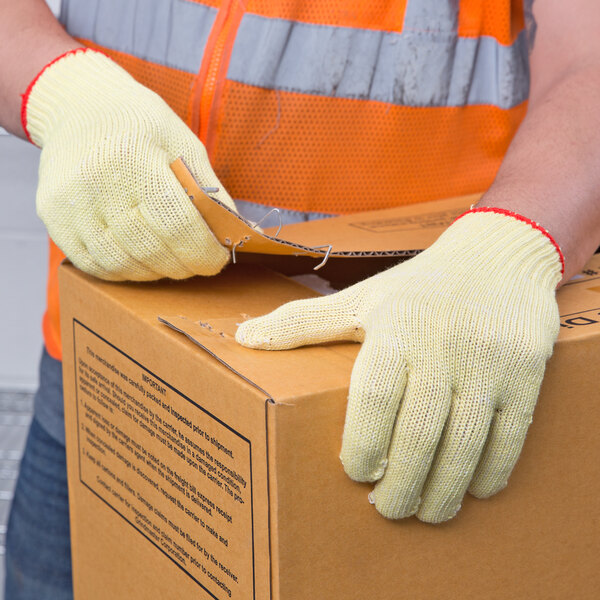 A person wearing Cordova Aramid / Cotton Work Gloves opening a box.