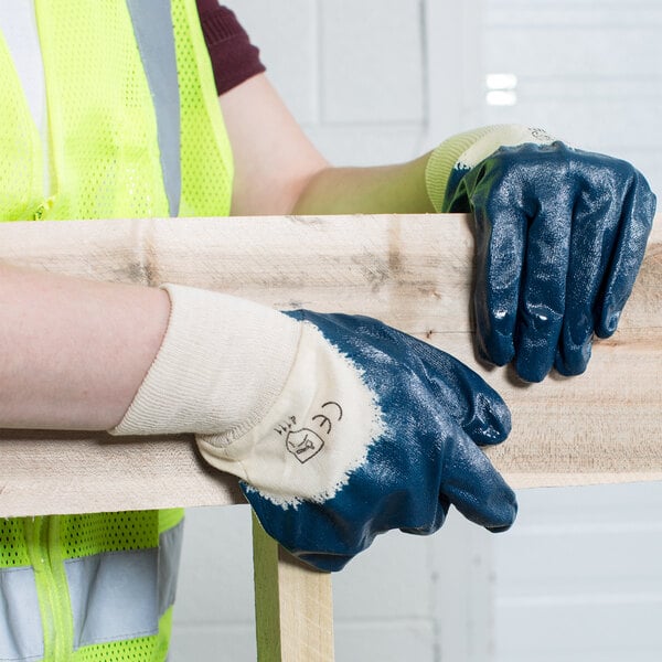 A person wearing Cordova blue nitrile gloves holds a piece of wood.