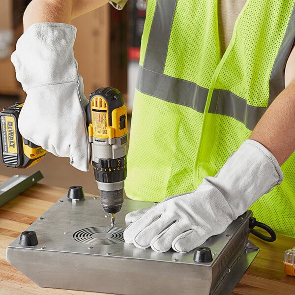 A person wearing Cordova gray leather welder's gloves using a drill to drill holes in a metal box.