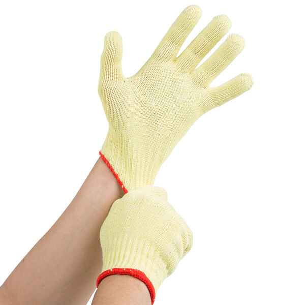 A pair of yellow Cordova work gloves with red trim being worn on a pair of hands.